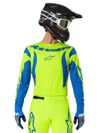 Alpinestars 2025 Fluid Haul Jersey, maglia da motocross, giallo neon e blu, con logo Alpinestars blu sul petto, indossata con equipaggiamento coordinato tra cui casco nero e guanti blu, vestibilità atletica per il fuoristrada