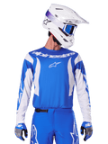 Alpinestars 2025 Fluid Haul Jersey, maglia da motocross, blu e bianco, indossata con pantaloni e guanti coordinati, casco bianco con occhiali blu, set di abbigliamento MX coordinato per guida off-road
