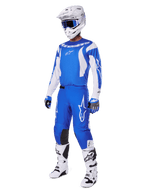 Pilota di motocross che indossa il set completo 2025 Fluid Haul, maglia e pantaloni blu e bianchi con logo Alpinestars, casco bianco con occhiali blu, stivali bianchi e guanti blu, completo da gara coordinato per motocross fuoristrada.