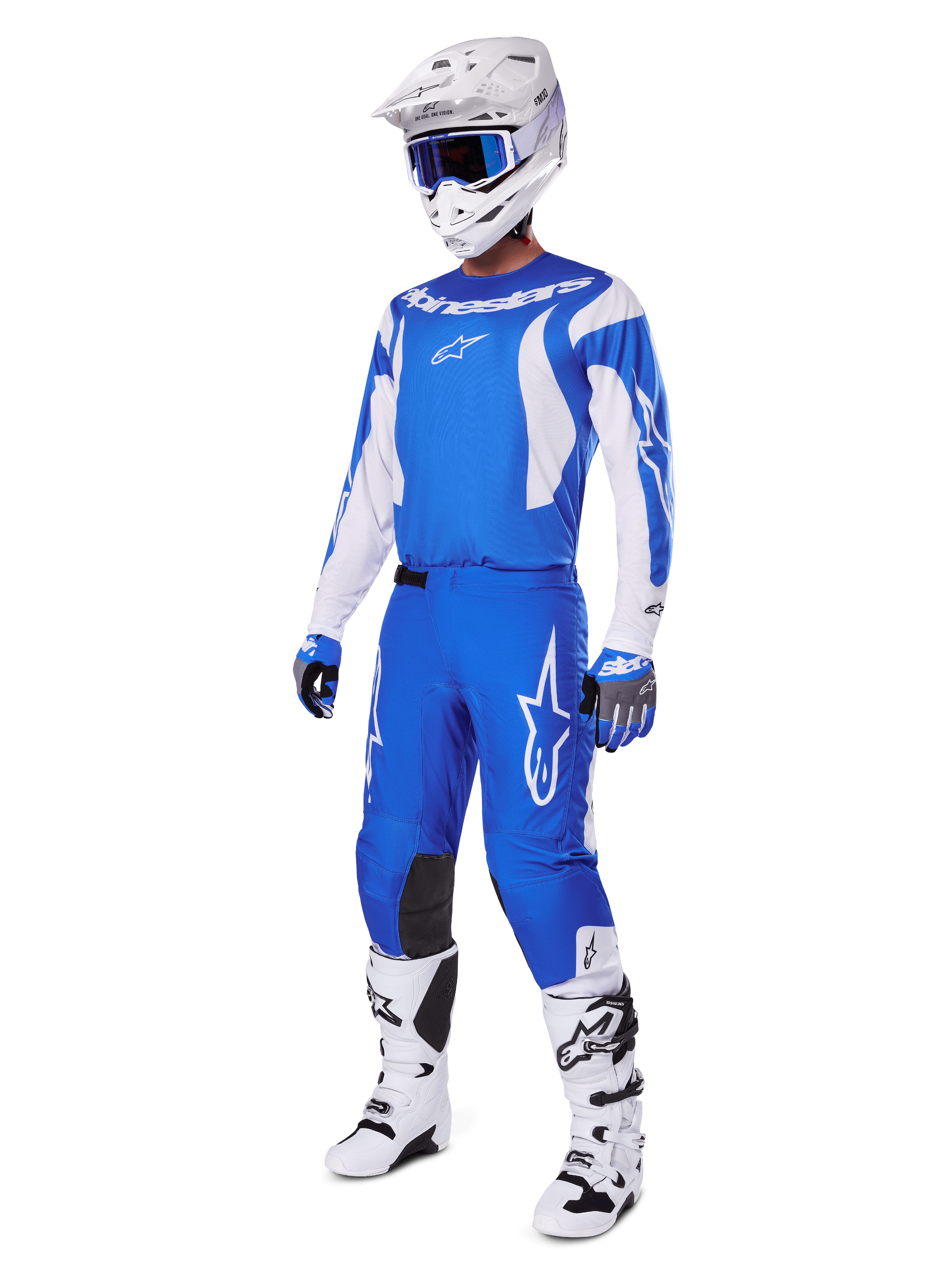 Pilota di motocross che indossa il set completo 2025 Fluid Haul, maglia e pantaloni blu e bianchi con logo Alpinestars, casco bianco con occhiali blu, stivali bianchi e guanti blu, completo da gara coordinato per motocross fuoristrada.