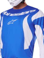 Alpinestars 2025 Fluid Haul Jersey, blu e bianco, indossata da un pilota con casco bianco, con scritta Alpinestars e logo A-star bianchi, vestibilità atletica, materiale leggero e traspirante per motocross e off-road