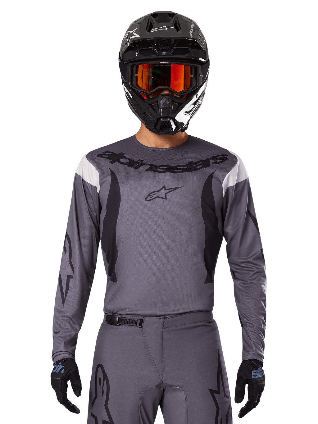 Pilota di motocross con maglia e set di abbigliamento Fluid Haul 2025, grigio con accenti neri e bianchi, maniche lunghe e loghi evidenti, casco nero con occhiali arancioni e guanti neri, outfit coordinato per corse fuoristrada