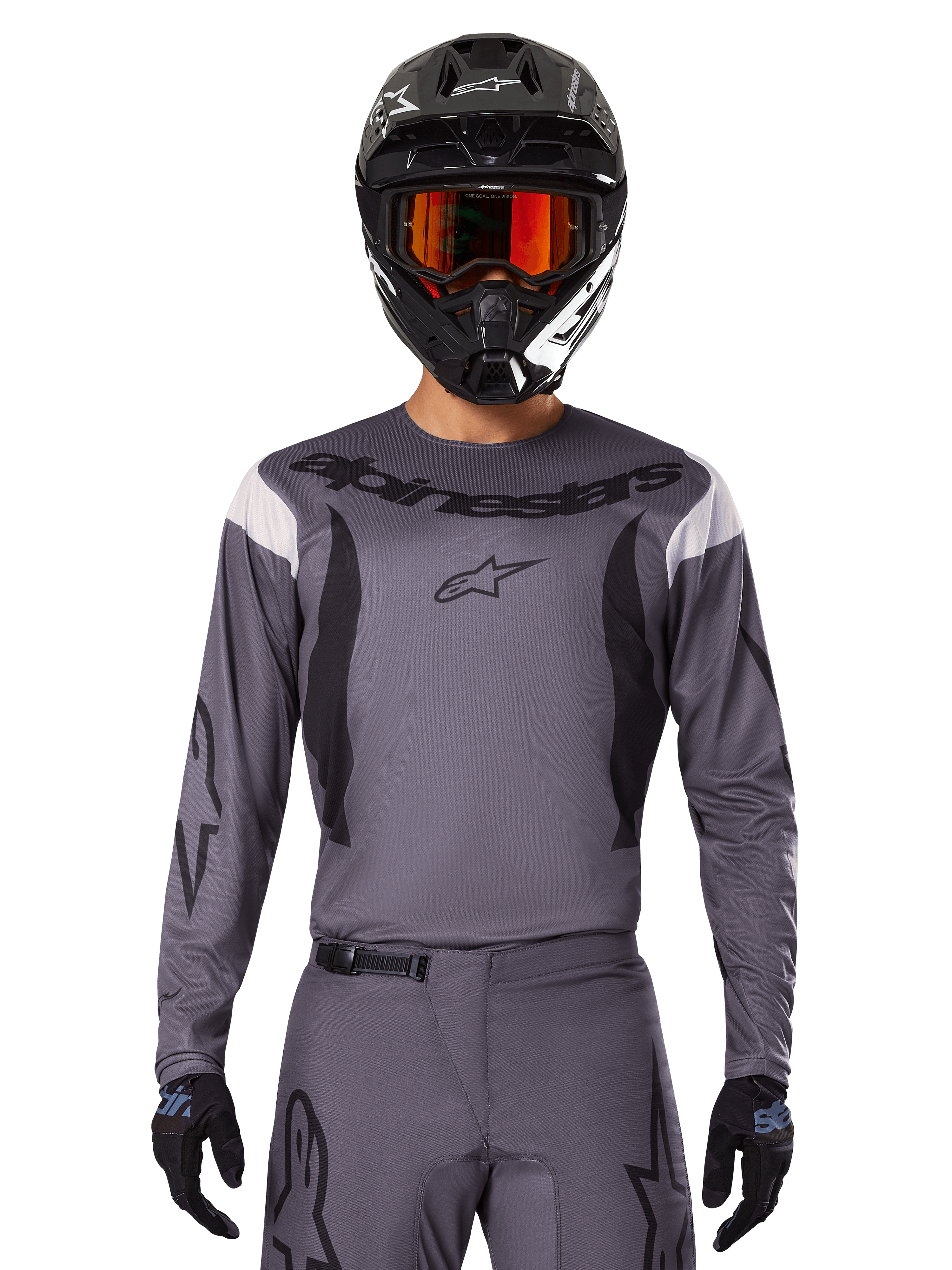 Pilota di motocross con maglia e set di abbigliamento Fluid Haul 2025, grigio con accenti neri e bianchi, maniche lunghe e loghi evidenti, casco nero con occhiali arancioni e guanti neri, outfit coordinato per corse fuoristrada