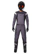 Alpinestars 2025 Fluid Haul Gear Set, abbigliamento da motocross, grigio, maglia e pantaloni grigi con dettagli neri, casco nero con occhiali arancioni, stivali neri con loghi bianchi, completo da gara coordinato per prestazioni fuoristrada