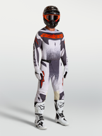 Alpinestars maglia e completo Techstar Swan, abbigliamento motocross da uomo su modello lilla e grigio con rosso fluo.
