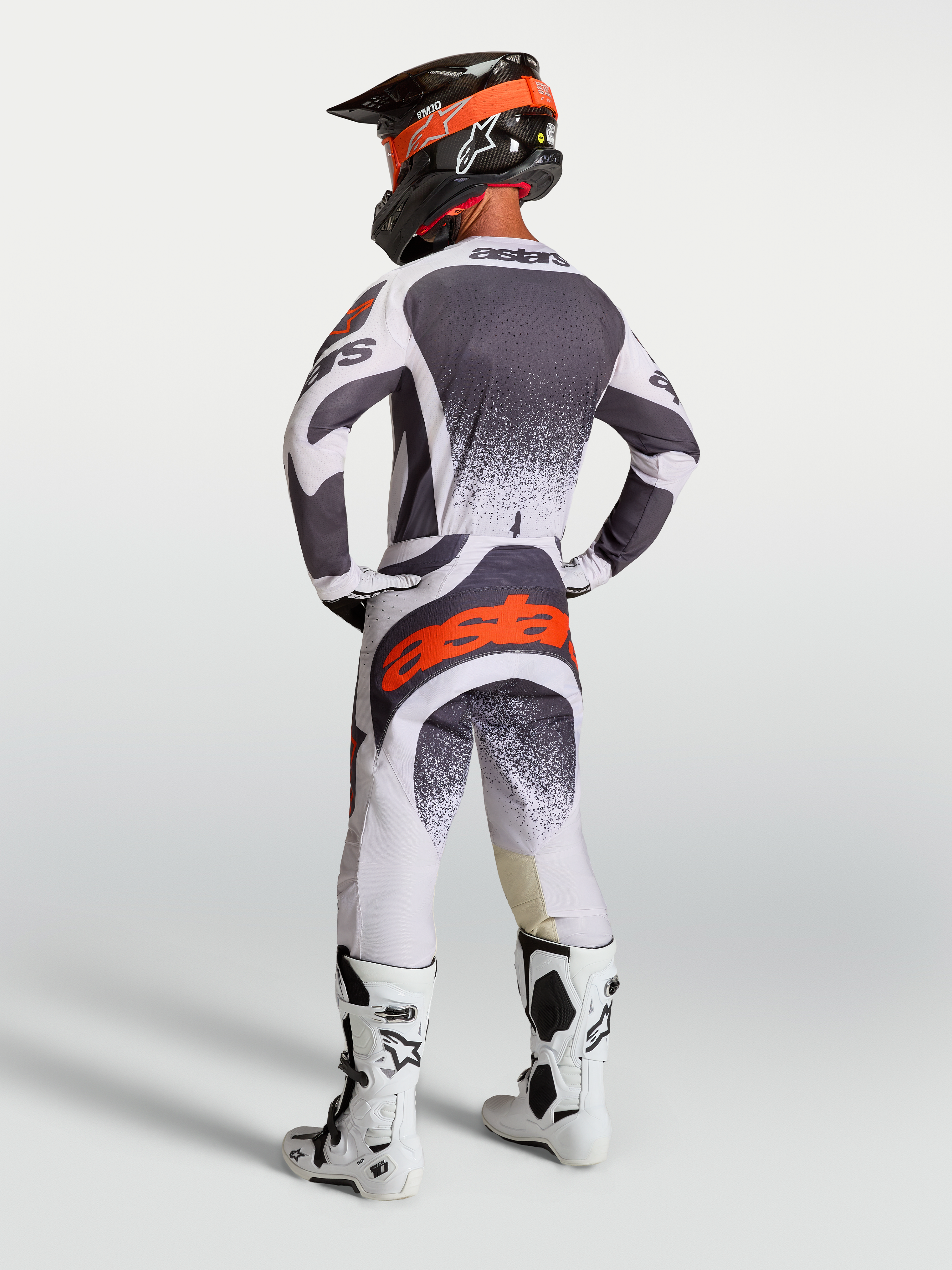 Alpinestars maglia e completo Techstar Swan, abbigliamento motocross per uomo grigio scuro e rosso fluo, visto di schiena.