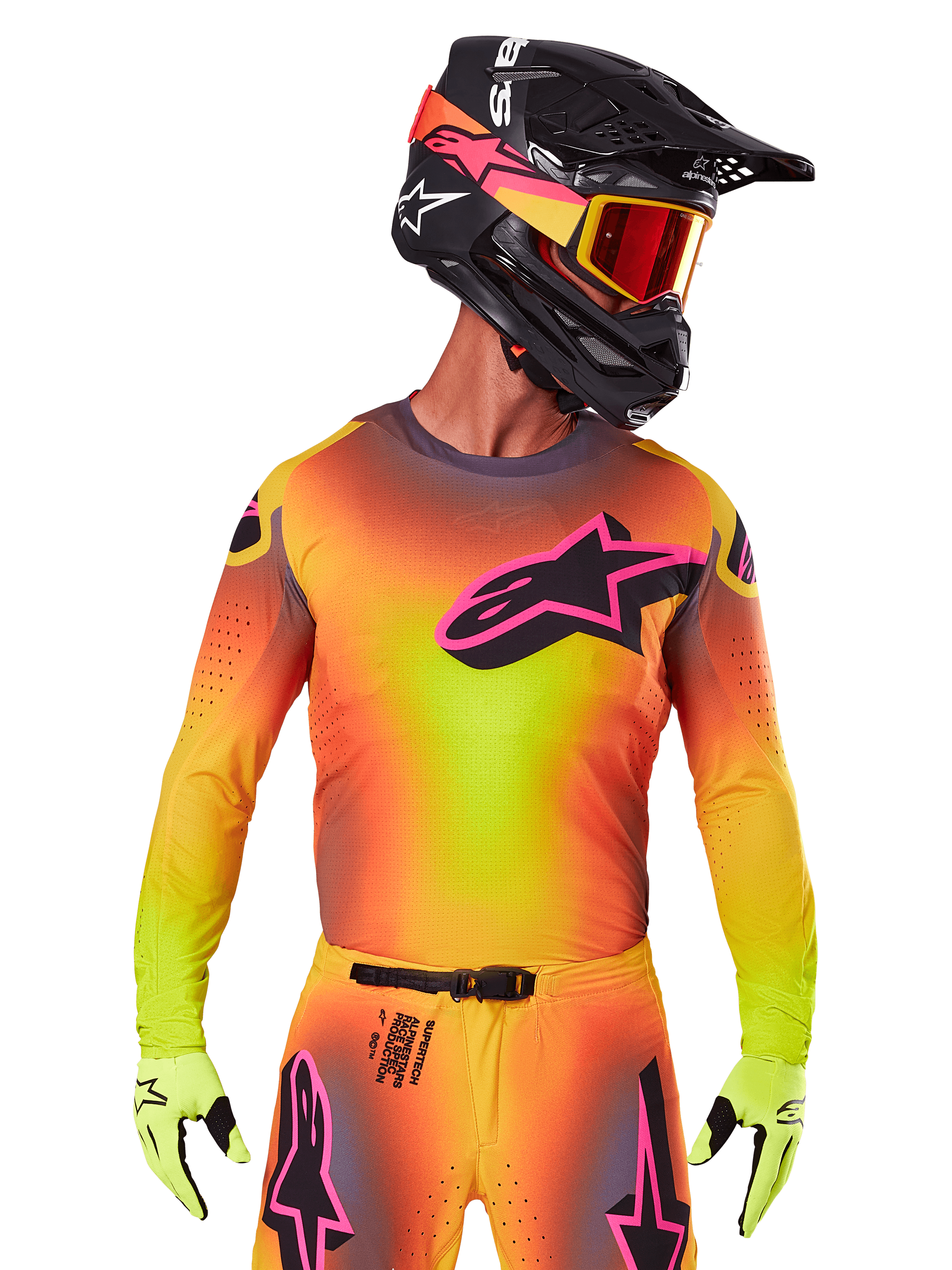 Pilota di motocross con maglia Supertech Lipan 2025, vivace sfumatura gialla, arancione e rosa, grande logo a stella Alpinestars nero con profilo rosa sul petto, perforazioni laser per la ventilazione, vestibilità atletica da gara, abbinata a pantaloni coordinati, guanti gialli e casco nero con maschera.
