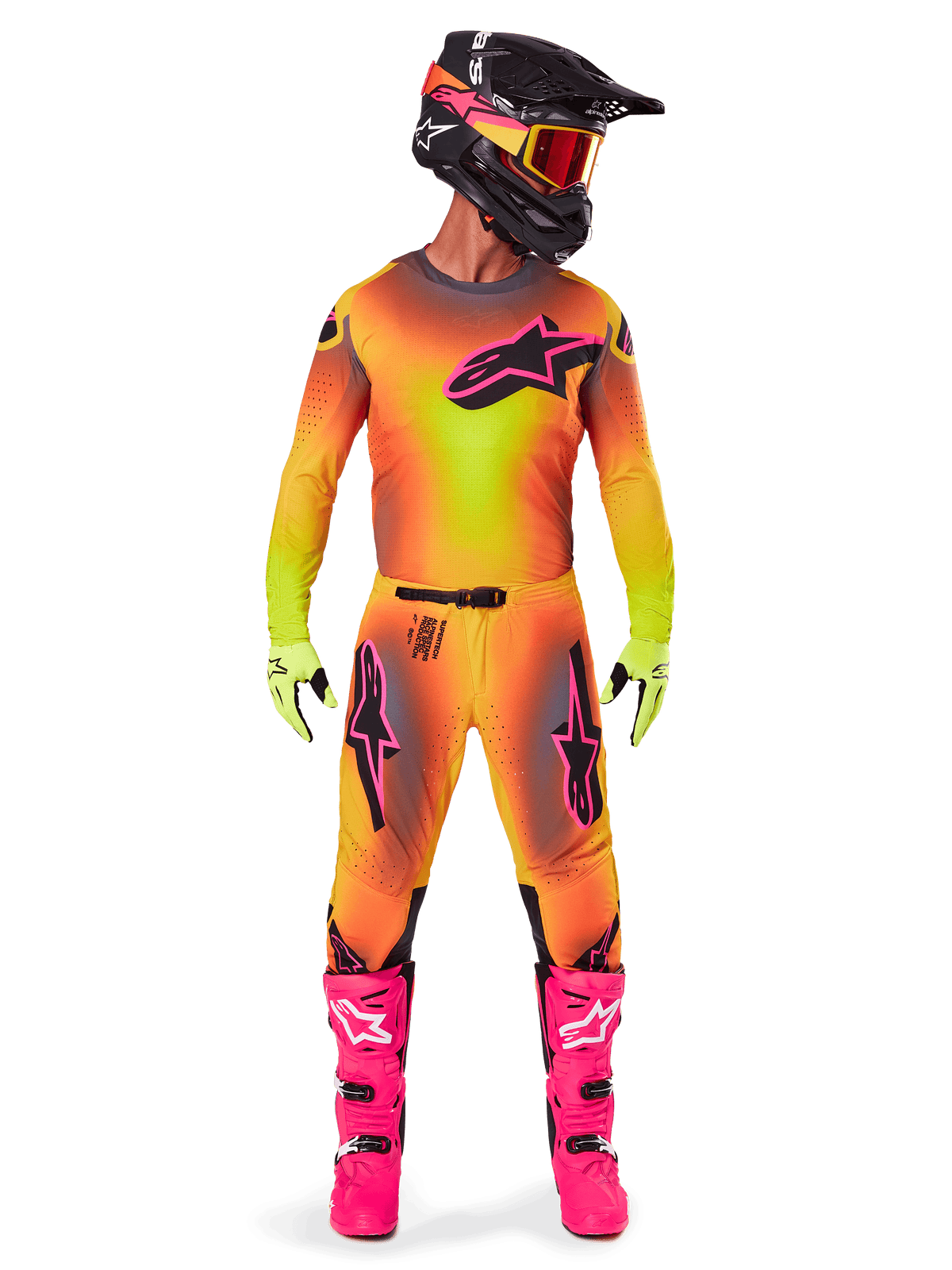 Pilota di motocross con abbigliamento da gara completo, maglia e pantaloni Supertech Lipan 2025 in una sfumatura gialla e arancione con accenti rosa, casco nero con grafiche rosa coordinate, stivali rosa acceso e guanti verde lime, completo da corsa off-road Alpinestars coordinato.