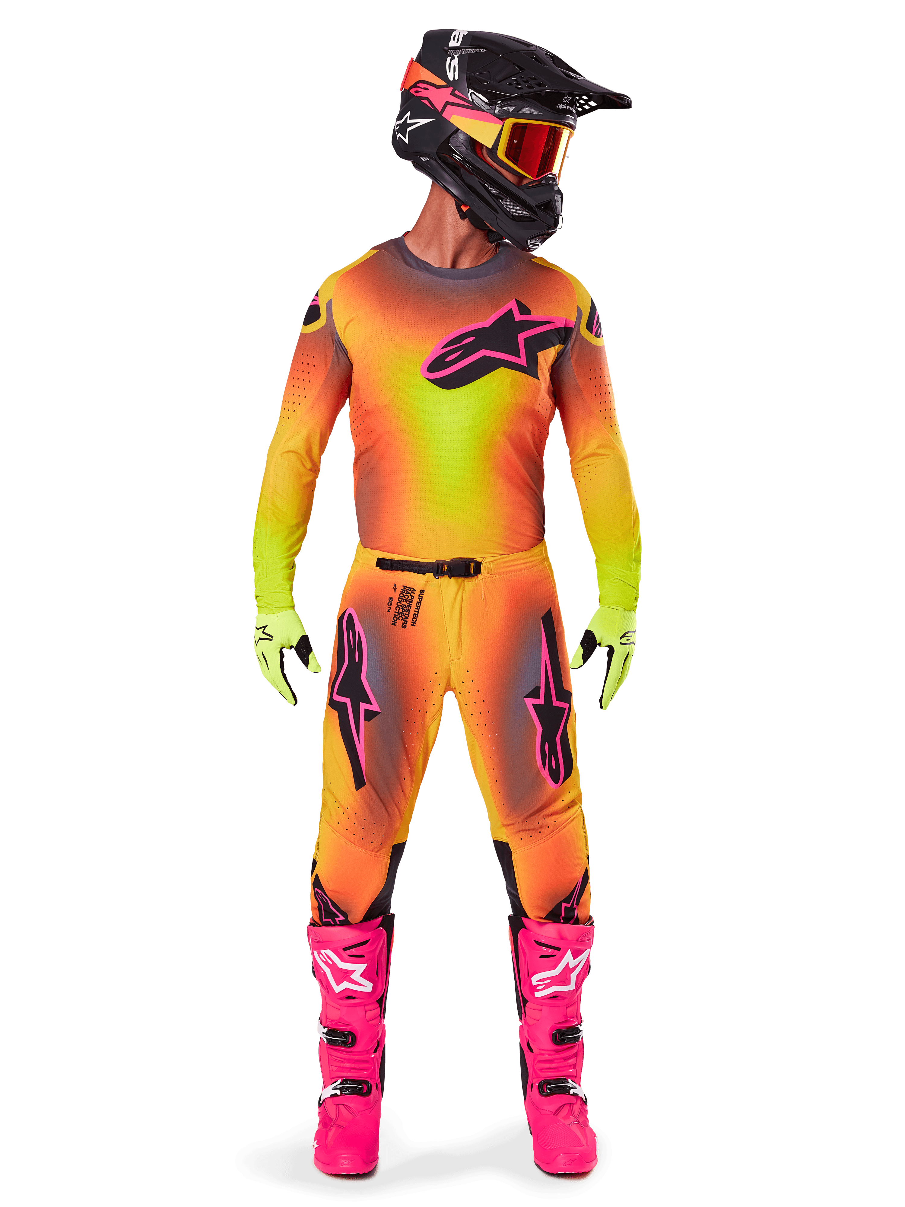 Pilota di motocross con abbigliamento da gara completo, maglia e pantaloni Supertech Lipan 2025 in una sfumatura gialla e arancione con accenti rosa, casco nero con grafiche rosa coordinate, stivali rosa acceso e guanti verde lime, completo da corsa off-road Alpinestars coordinato.