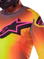 Primo piano della maglia Alpinestars Supertech Lipan 2025 in giallo e rosa, caratterizzata da un vivace design sfumato, un grande logo a stella nero con bordo rosa sul petto e perforazioni tagliate al laser visibili per un flusso d'aria ottimizzato.