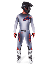 Motocross rider wearing the Alpinestars 2025 Supertech Lipan Jersey in Gray Orange Fluo, featuring a gray gradient design and orange logo, paired with matching motocross pants, black helmet, white boots, and orange gloves, coordinated pro-level racing gear.