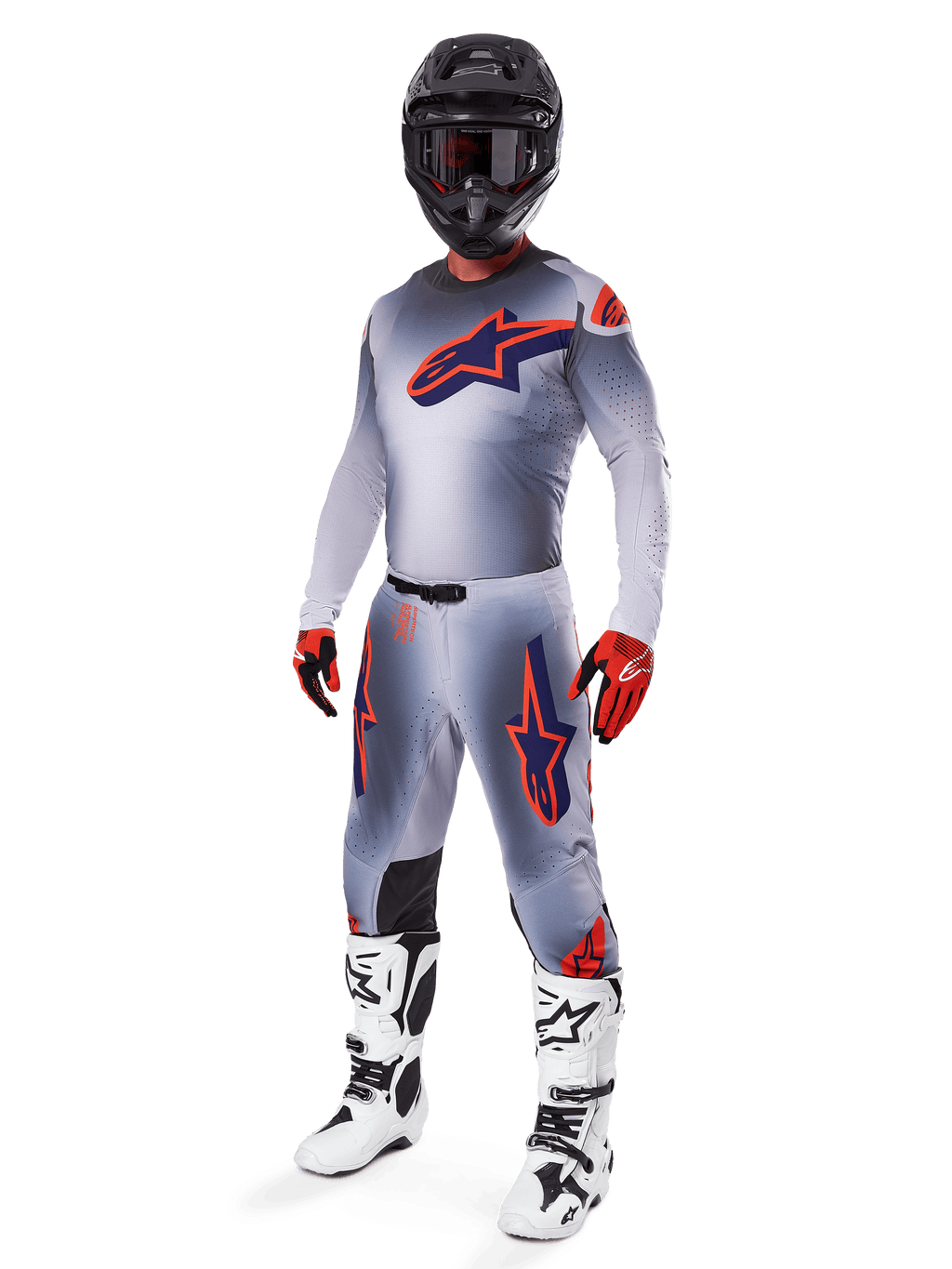 Pilota di motocross con maglia Alpinestars Supertech Lipan 2025 in grigio e arancione fluo, pantaloni grigi coordinati con accenti arancioni, casco nero, stivali bianchi e neri e guanti arancioni e neri, set professionale per gare fuoristrada