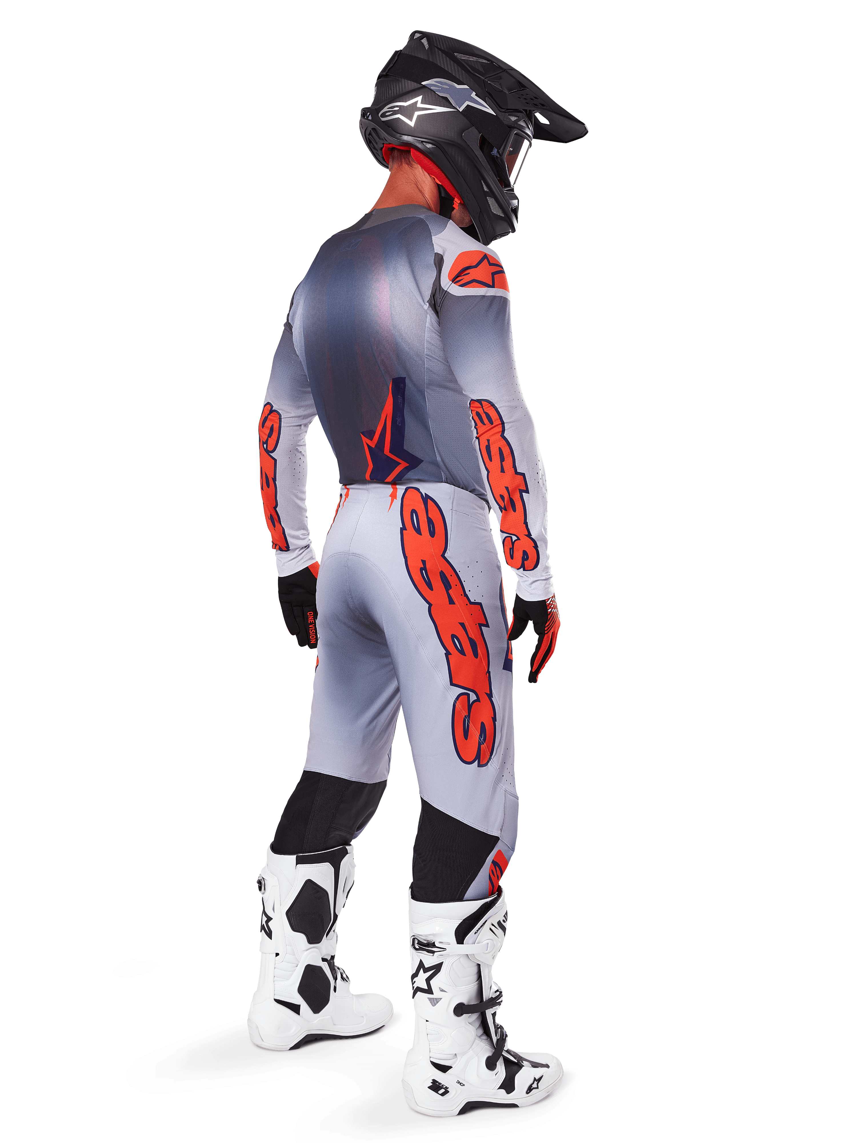 Pilota di motocross visto di profilo posteriore con maglia e pantaloni Alpinestars Supertech Lipan 2025, colori grigio e arancione fluo, logo Alpinestars arancione su maniche e gambe, casco nero e stivali bianchi, completo professionale per gare off-road