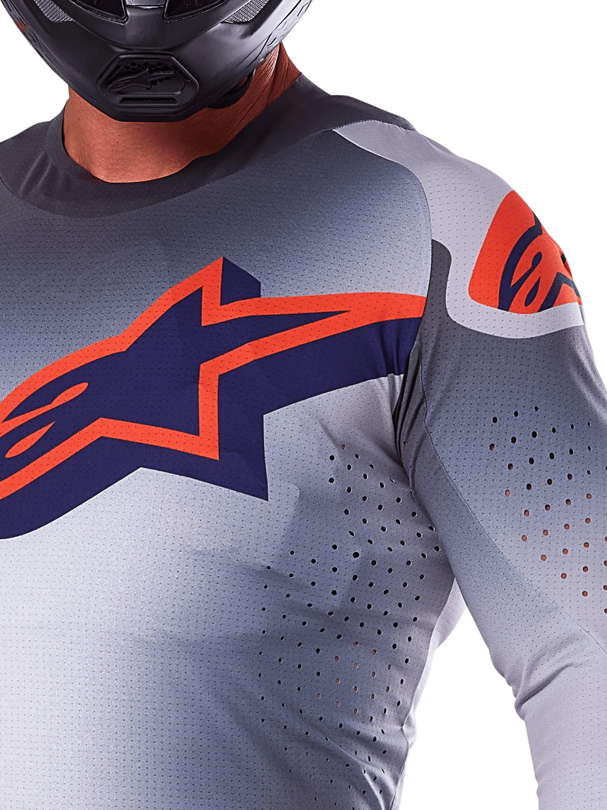 Close-up of a rider wearing the Alpinestars 2025 Supertech Lipan Jersey, Motocross Jersey, Gray and Orange Fluo, featuring a large orange Alpinestars logo on the chest, laser-cut ventilation holes, and a black helmet, professional racing gear.