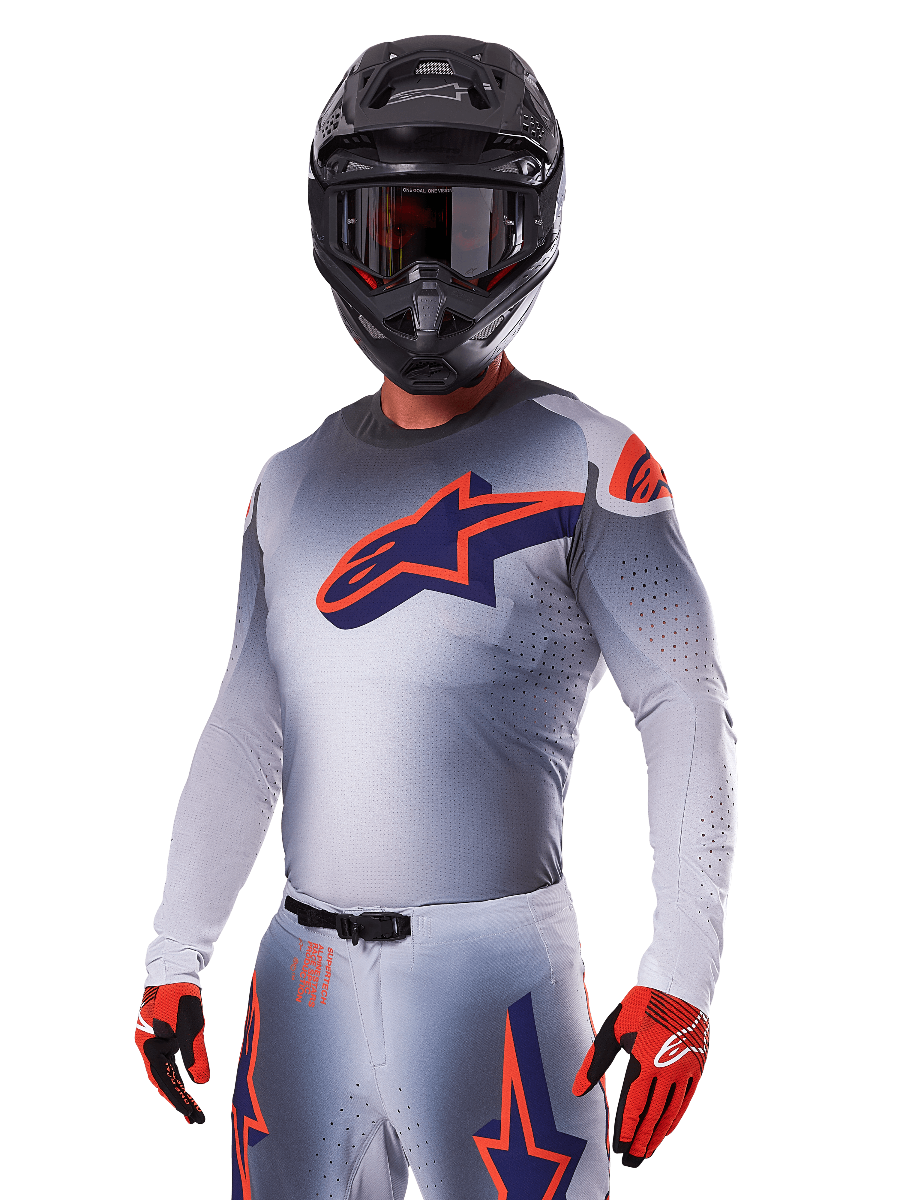 Pilota di motocross con Set Gear Alpinestars 2025 Supertech Lipan, maglia e pantaloni grigi con accenti blu navy e arancioni, casco nero opaco con occhiali e guanti rossi e neri, abbigliamento tecnico per corse fuoristrada