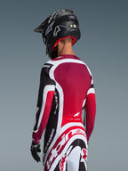 Vista posteriore di un pilota di motocross che indossa la maglia Supertech AFD Vista 2026 in nero, rosso e bianco, coordinata con pantaloni abbinati e un casco nero, con marchio Alpinestars in evidenza, pannelli in mesh rossi e vestibilità atletica racing.