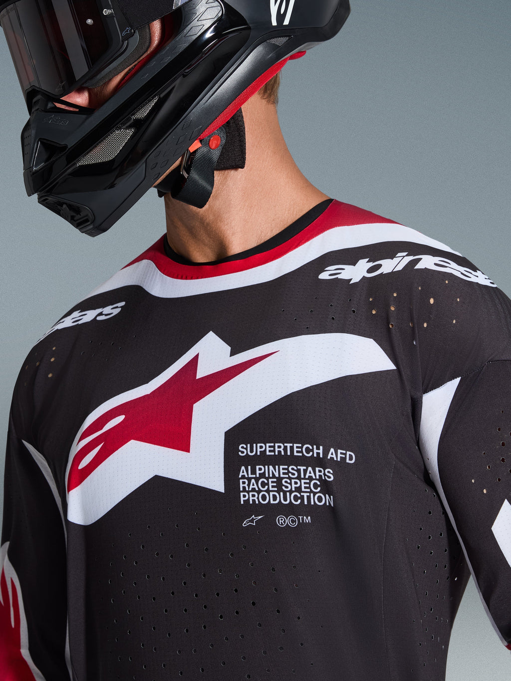 Alpinestars 2026 Supertech AFD Vista Jersey, nero, rosso e bianco, primo piano del petto con logo a stella Alpinestars e scritta 'Supertech AFD', fori di ventilazione tagliati al laser e struttura in mesh, indossata con casco da motocross nero.