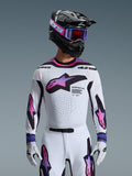 Pilota di motocross che indossa la maglia Supertech AFD Vista 2026 in bianco, viola e nero, con casco nero e logo rosa, occhiali viola e guanti bianchi coordinati, abbigliamento con vestibilità atletica progettato per prestazioni professionali off-road