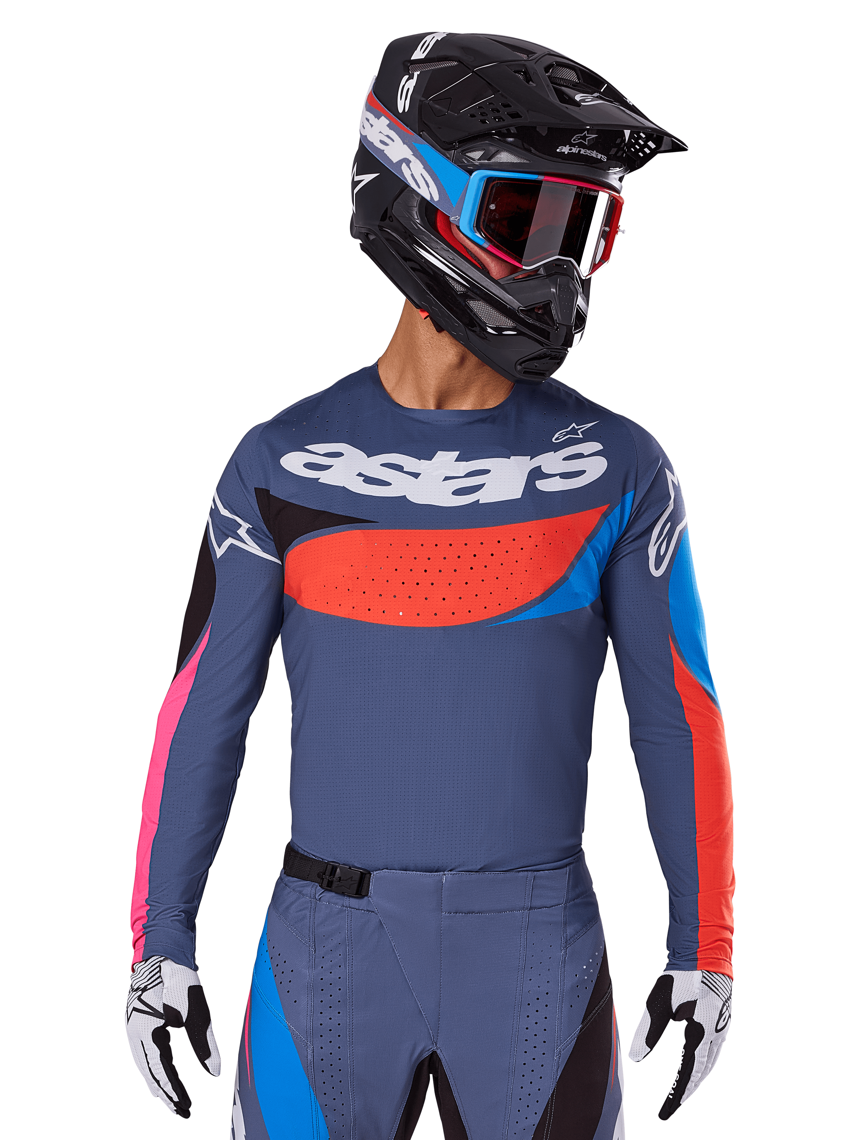 Alpinestars maglia Techstar Dreem 2025, maglia da motocross, grigio con accenti blu, rossi e rosa, con perforazioni laser e grande logo sul petto, indossata con pantaloni coordinati e casco da gara nero