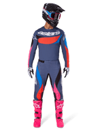 Alpinestars Techstar Dreem Gear Set 2025, pilota di motocross con equipaggiamento completo da gara, maglia e pantaloni grigio-blu con vivaci accenti rosa, arancione e blu ciano, grande logo 'astars' sul petto, stivali rosa acceso, casco nero con maschera, completo coordinato per motocross professionale