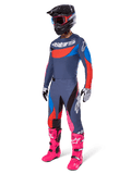 Alpinestars Set Techstar Dreem 2025, abbigliamento completo da motocross con maglia grigia e blu e dettagli rossi, pantaloni coordinati con tocchi di rosa, casco nero, stivali rosa acceso e guanti bianchi e neri