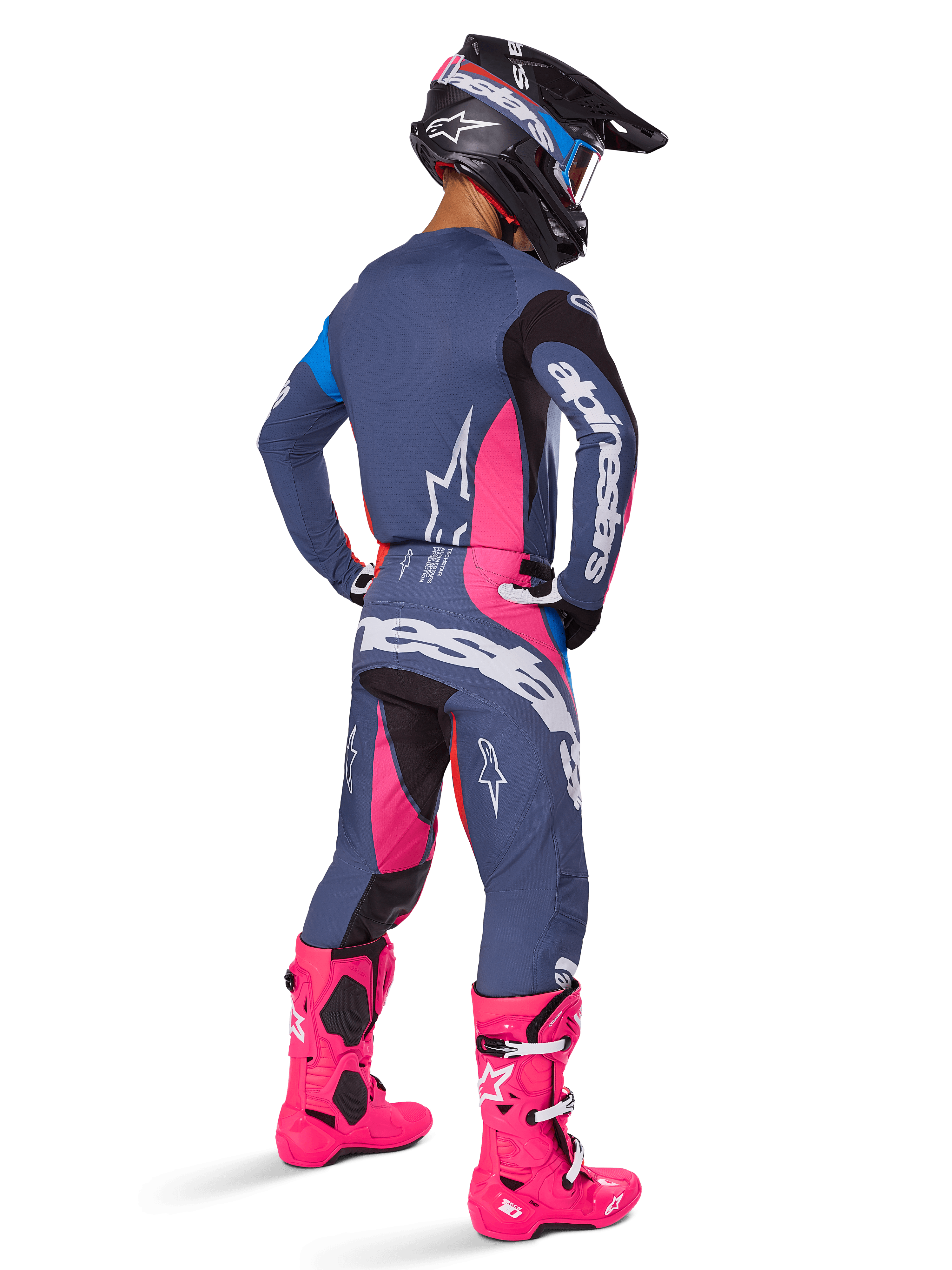 Pilota di motocross visto da dietro, completo Alpinestars 2025 Techstar Dreem, grigio con vivaci accenti rosa e bianchi, casco nero e bianco e stivali rosa acceso, abbigliamento completo da gara per motocross