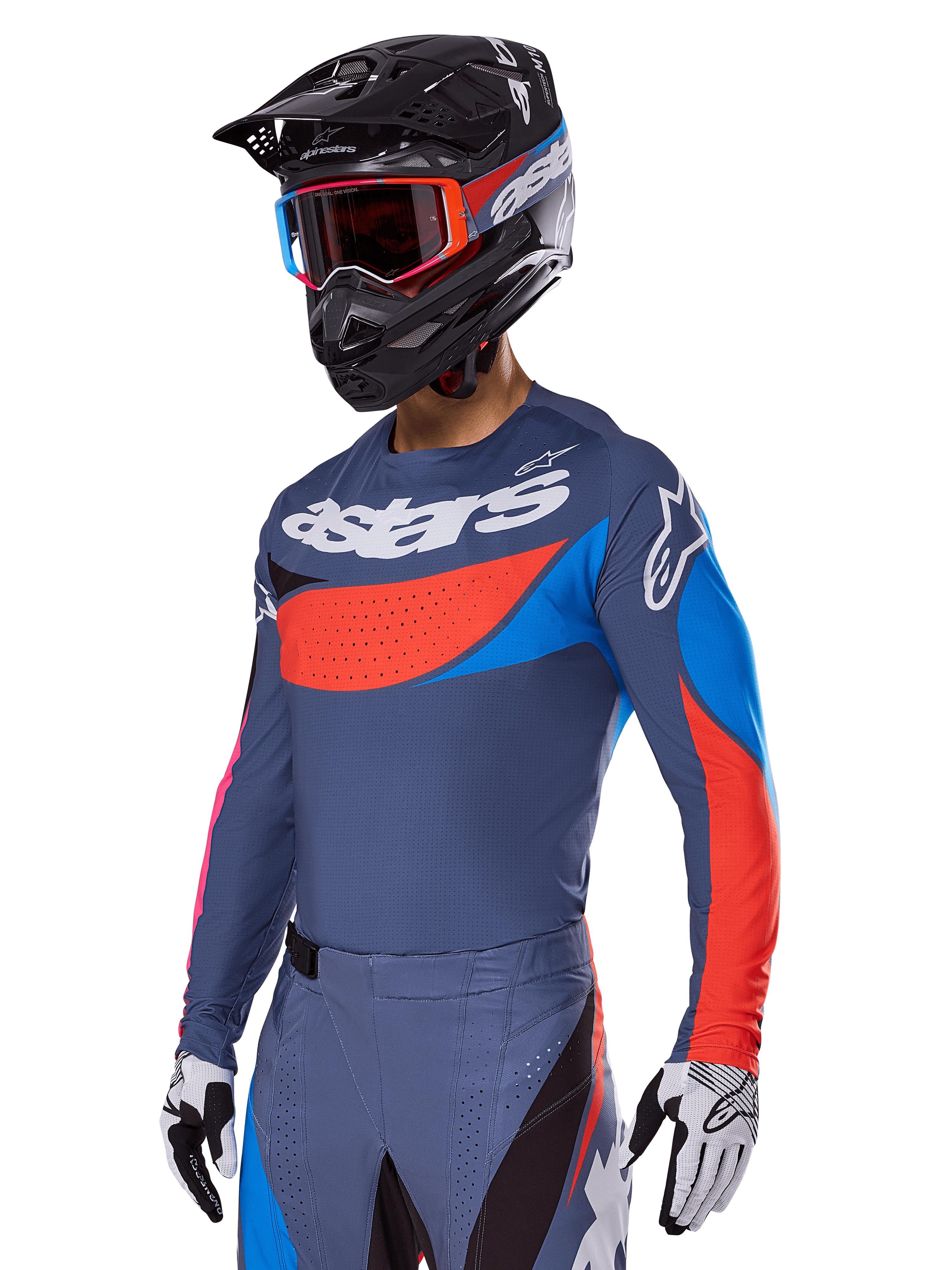 Completo motocross Alpinestars Techstar Dreem 2025, pilota che indossa maglia e pantaloni grigio ardesia con grafiche rosse e blu e logo 'astars' sul petto, abbinato a casco nero, maschera con montatura rossa e guanti da gara bianchi