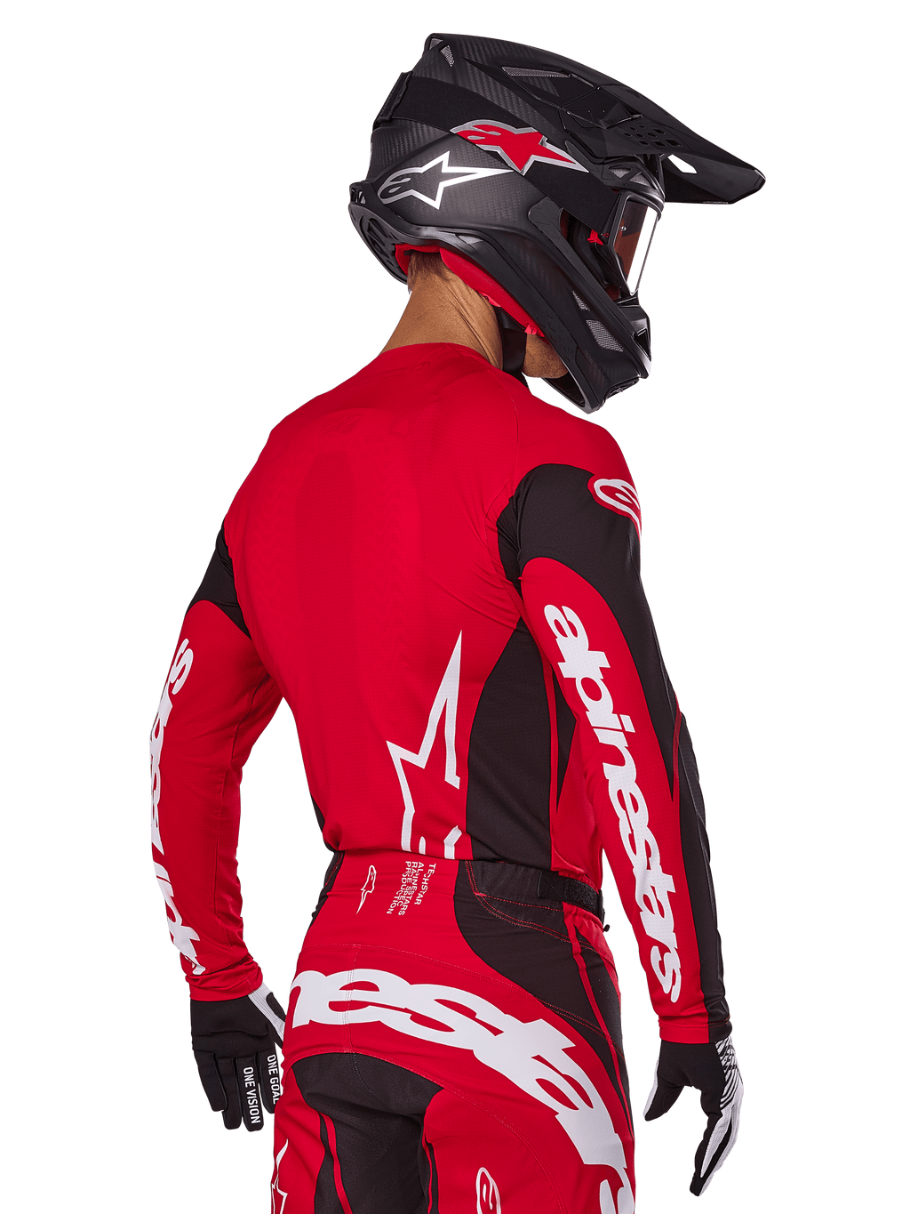 Pilota di motocross visto da dietro con completo Alpinestars Techstar Dreem 2025, maglia rossa e nera con loghi bianchi sulle maniche, pantaloni coordinati rossi e neri con logo bianco sulla seduta, casco in carbonio nero con accenti rossi, guanti bianchi e neri, abbigliamento professionale da gara fuoristrada