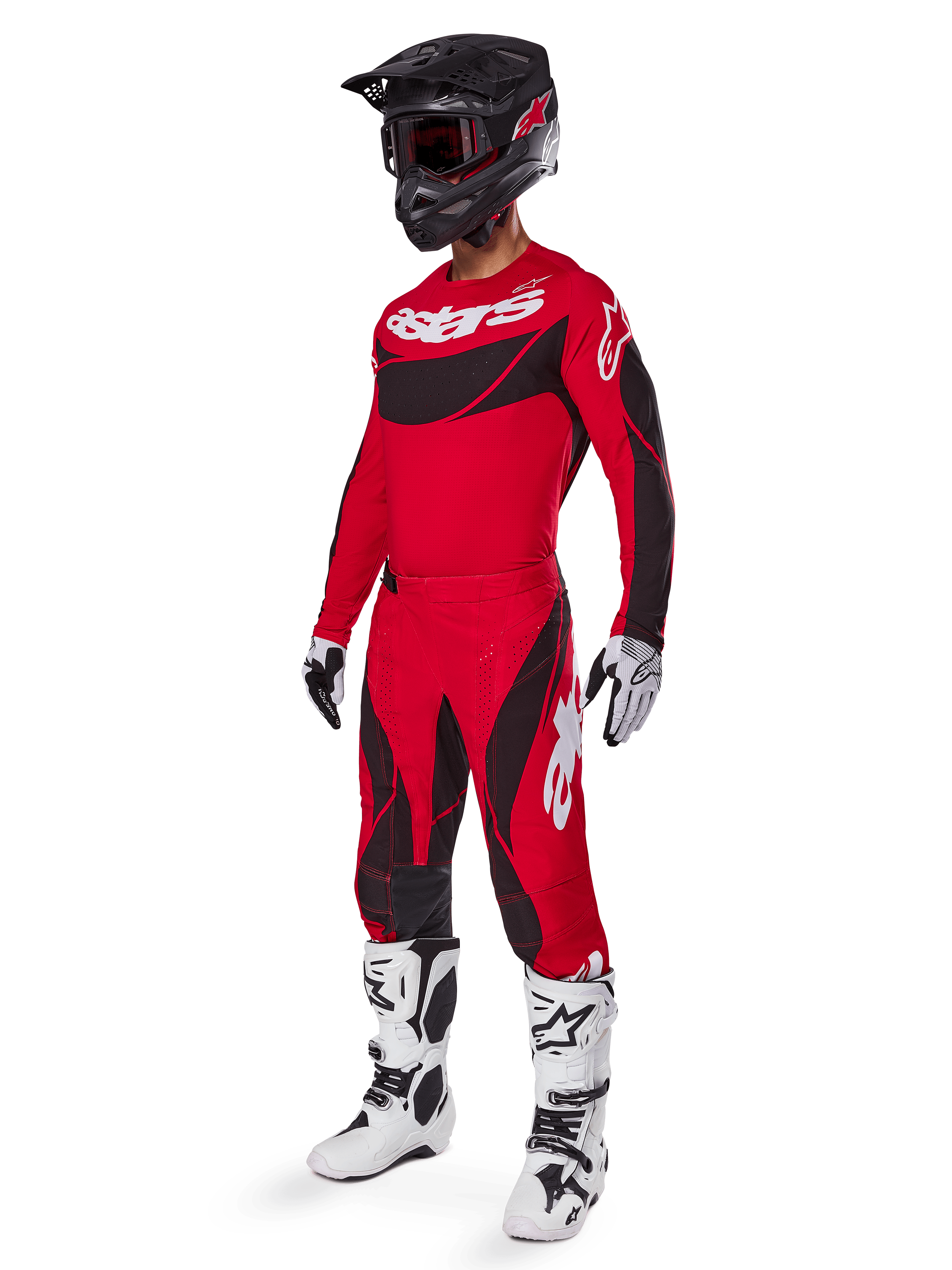 Vista a figura intera di un pilota di motocross con il completo Techstar Dreem 2025 in rosso brillante e nero, con maglia tecnica con branding bianco, pantaloni coordinati in ripstop elasticizzato, casco nero con visiera rossa, guanti bianchi e neri e stivali Tech bianchi, abbigliamento da gara specializzato per competizioni fuoristrada.