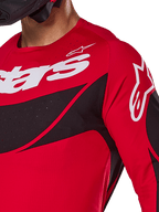 Maglia Alpinestars 2025 Techstar Dreem, maglia da motocross, rosso acceso e nero, vista ravvicinata di petto e spalla con logo bianco, pannelli diagonali neri con perforazioni tagliate al laser per la ventilazione, vestibilità atletica da gara per prestazioni fuoristrada.
