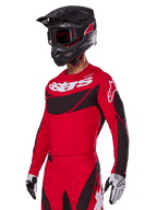Set completo Alpinestars Techstar Dreem 2025, maglia e pantaloni da motocross rossi con accenti neri e bianchi, indossati con casco e occhiali neri, guanti bianchi e neri, con logo 'astars' in evidenza, progettato per gare off-road ad alte prestazioni