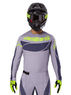 Maglia e set gear Techstar Dreem 2025, completo da gara motocross, grigio chiaro e grigio scuro con dettagli giallo neon, marchio 'astars', indossato con casco nero, occhiali e guanti coordinati, materiale tecnico traforato per prestazioni off-road