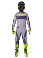 Pilota di motocross con abbigliamento completo da gara Alpinestars, Maglia Techstar Dreem 2025 in grigio e grigio scuro con loghi giallo neon, pantaloni coordinati grigio e grigio scuro, stivali giallo neon e neri, casco nero con accenti neon, completo professionale per motocross