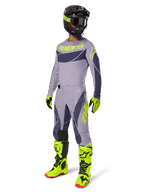 Pilota di motocross che indossa la maglia Techstar Dreem 2025 in grigio e grigio scuro con accenti giallo neon, abbigliamento completo da gara con pantaloni grigi abbinati, stivali e guanti giallo neon e casco nero, outfit coordinato per prestazioni fuoristrada