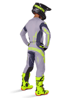 Alpinestars Techstar Dreem Jersey 2025, maglia da motocross, grigio e grigio scuro, indossata con pantaloni coordinati e stivali giallo neon brillante, vista posteriore che mostra il branding giallo neon e vestibilità atletica per corse fuoristrada