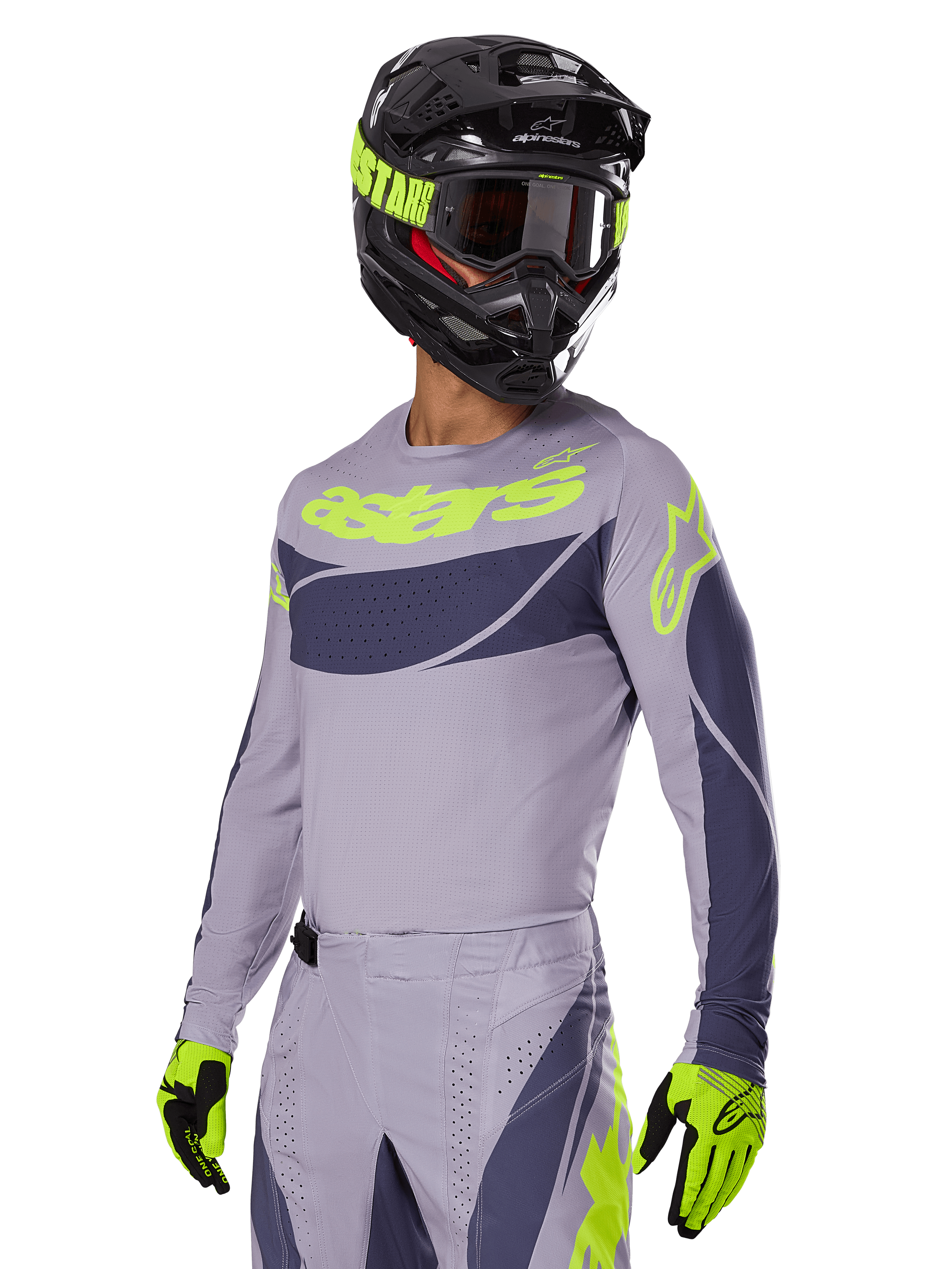 Pilota di motocross che indossa la maglia Alpinestars 2025 Techstar Dreem in grigio e grigio scuro, con logo 'astars' giallo neon sul petto, completata da casco, maschera e guanti coordinati per un look da gara off-road.