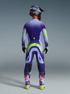 Set Gear Alpinestars Supertech Scenz 2026, pilota di motocross visto da dietro con completo viola e lilla e accenti giallo neon, maglia e pantaloni con design a pois sfumati, casco e occhiali coordinati, stivali viola chiaro con loghi rosa e suole giallo neon, abbigliamento professionale da gara motocross