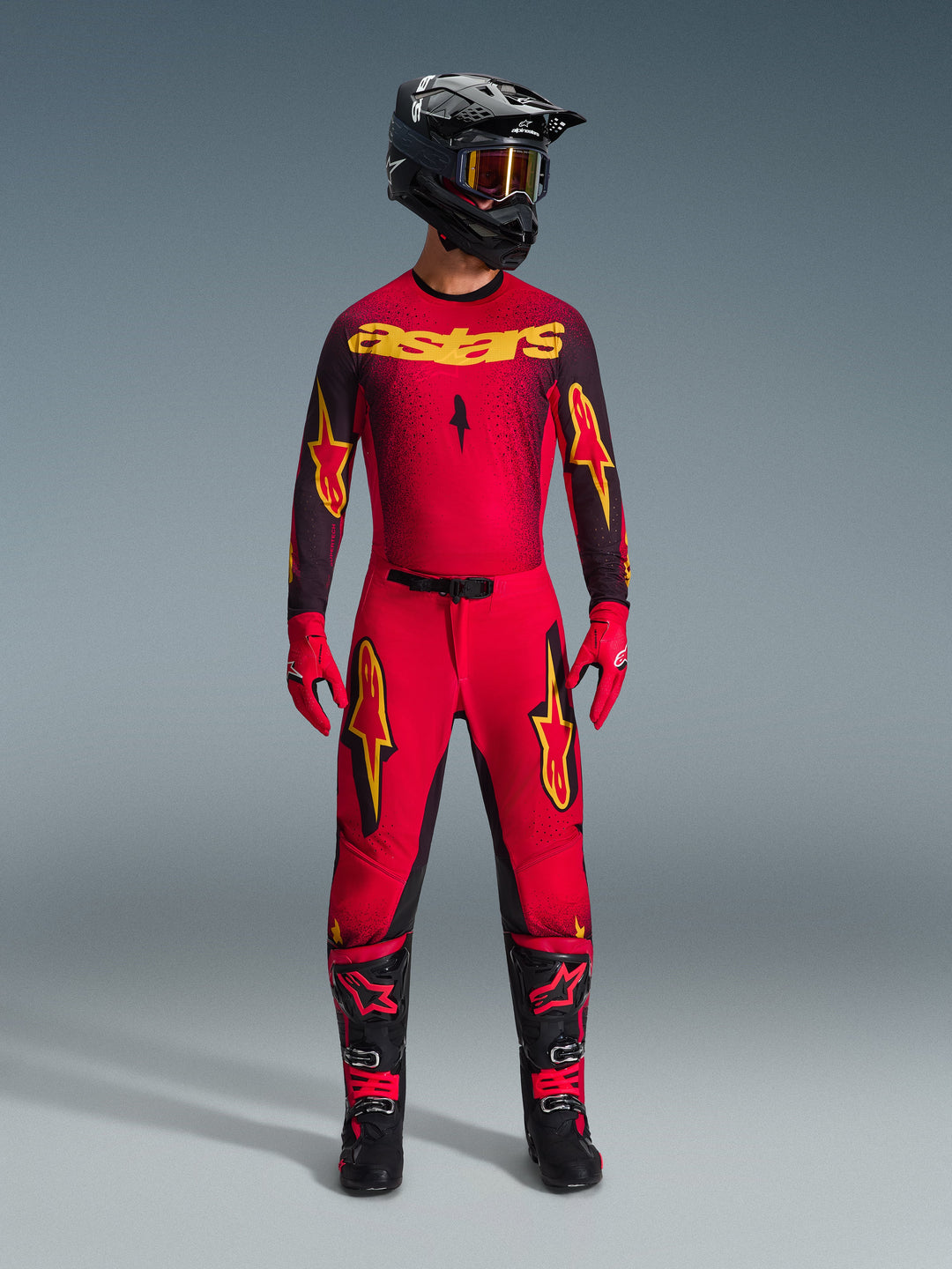 Set completo motocross Alpinestars Supertech Scenz 2026, completo da gara rosso e nero con grafiche gialle, composto da maglia professionale e pantaloni coordinati, abbinato a casco nero, guanti rossi e stivali da corsa neri, abbigliamento tecnico per competizioni fuoristrada