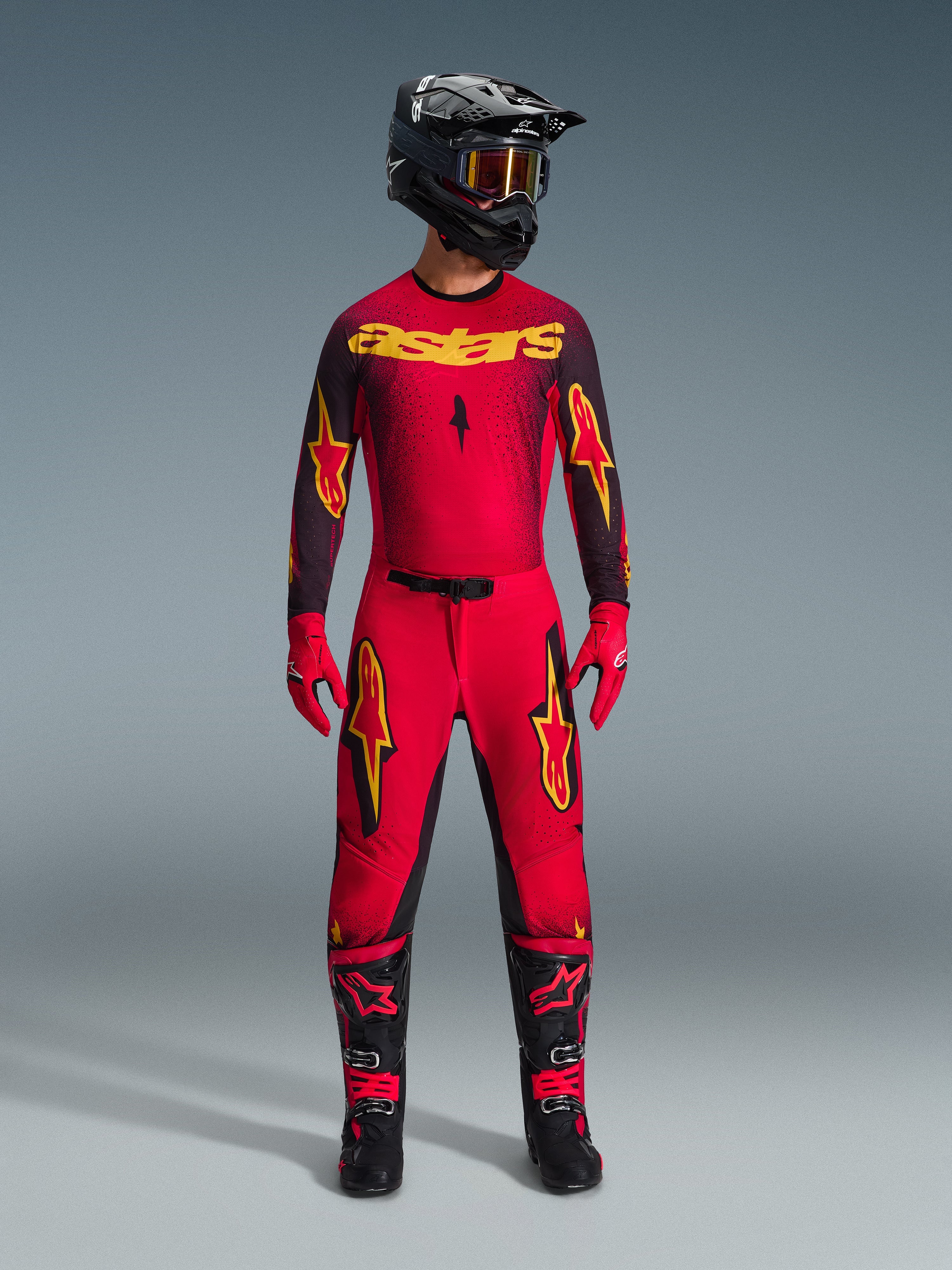 Set completo motocross Alpinestars Supertech Scenz 2026, completo da gara rosso e nero con grafiche gialle, composto da maglia professionale e pantaloni coordinati, abbinato a casco nero, guanti rossi e stivali da corsa neri, abbigliamento tecnico per competizioni fuoristrada