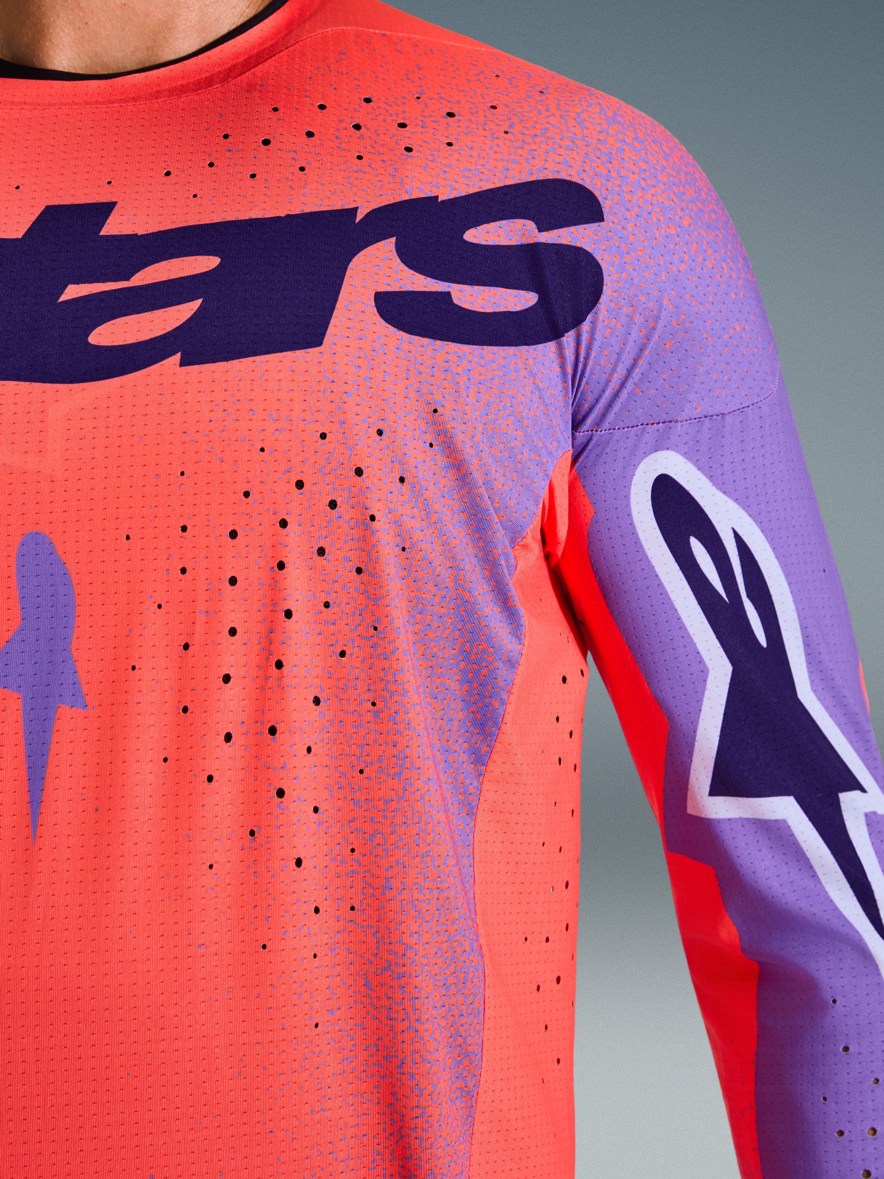 Alpinestars 2026 Supertech Scenz Jersey, maglia da motocross, corallo acceso e viola, vista ravvicinata con trama in mesh traspirante e perforazioni laser, grande logo viola sul petto e grafiche sulle maniche, per gare fuoristrada professionali.