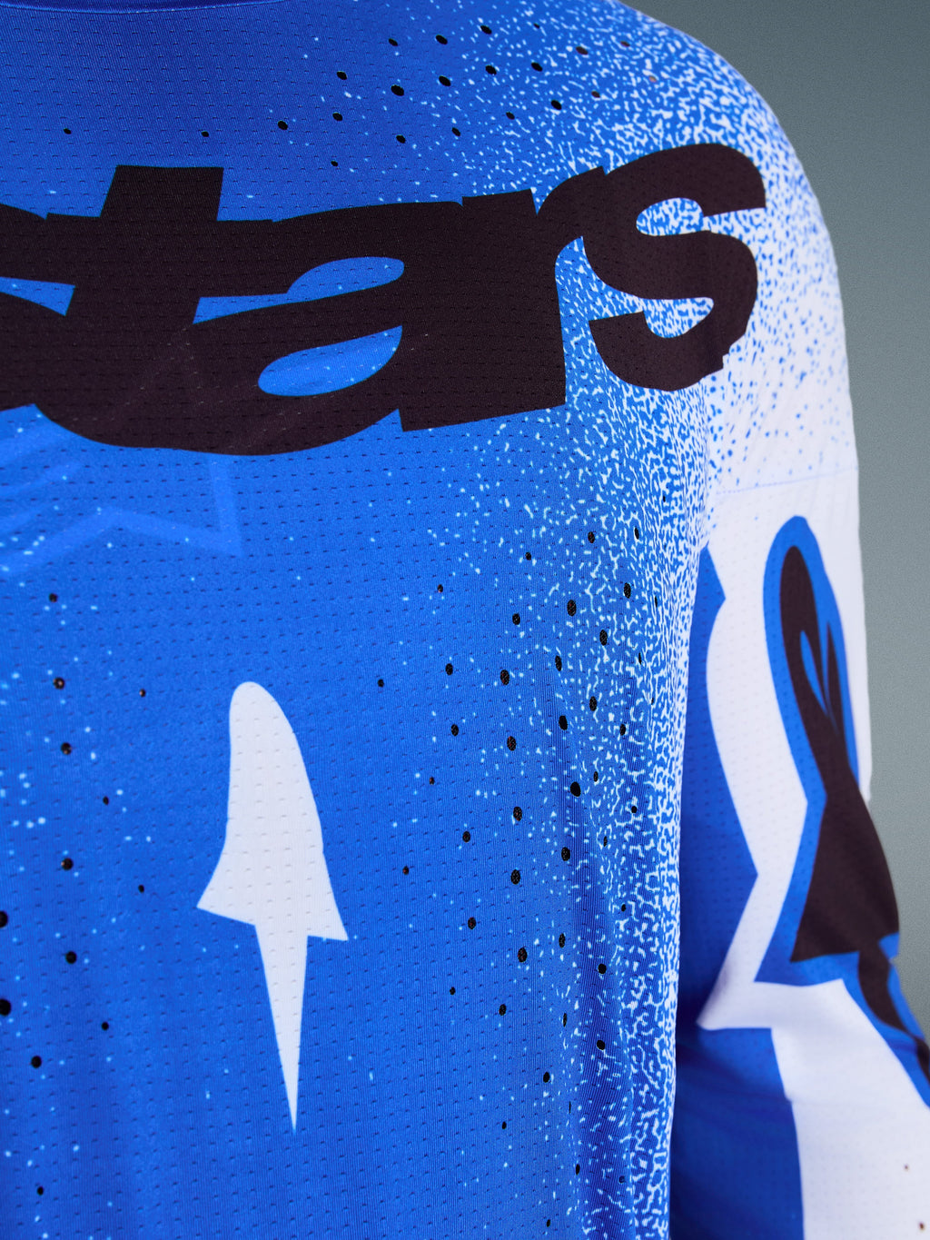 Alpinestars 2026 Supertech Scenz Jersey, primo piano del design Ucla Blue e bianco, con perforazioni tagliate al laser per la ventilazione, branding 'stars' nero e tessuto in mesh traspirante per gare di motocross professionali