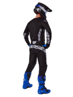 Pilota di motocross visto da dietro che indossa il set Alpinestars 2025 Racer Graphite, maglia e pantaloni nero e grigio con branding grigio, abbinati a stivali da motocross blu acceso, casco nero e blu e guanti blu, abbigliamento completo da fuoristrada ad alte prestazioni.
