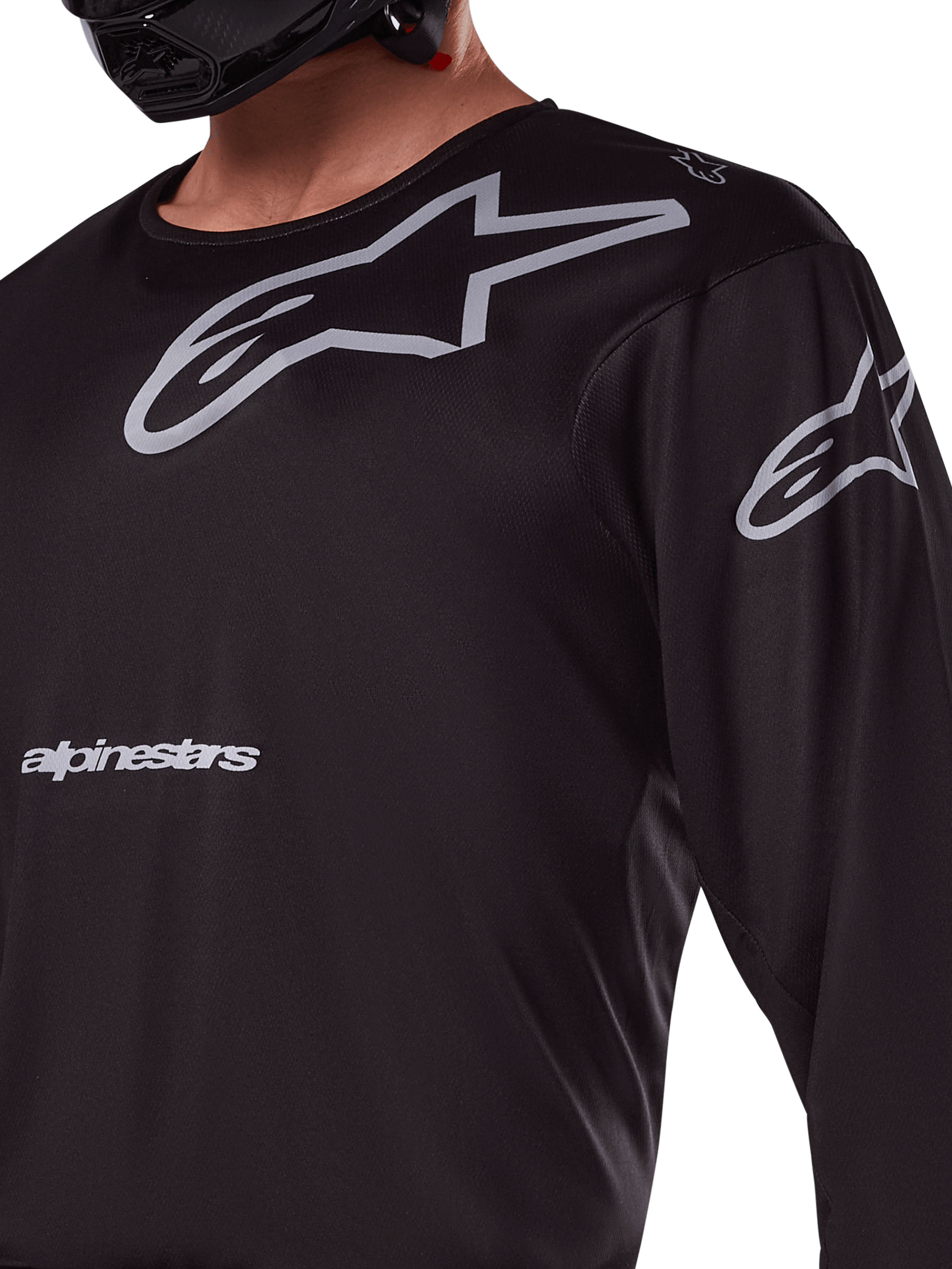 Alpinestars 2025 Racer Graphite Jersey, maglia da motocross nero e grigio, primo piano del pilota con marchio Alpinestars e loghi A-star grigi, materiale in politessuto tecnico per guida fuoristrada