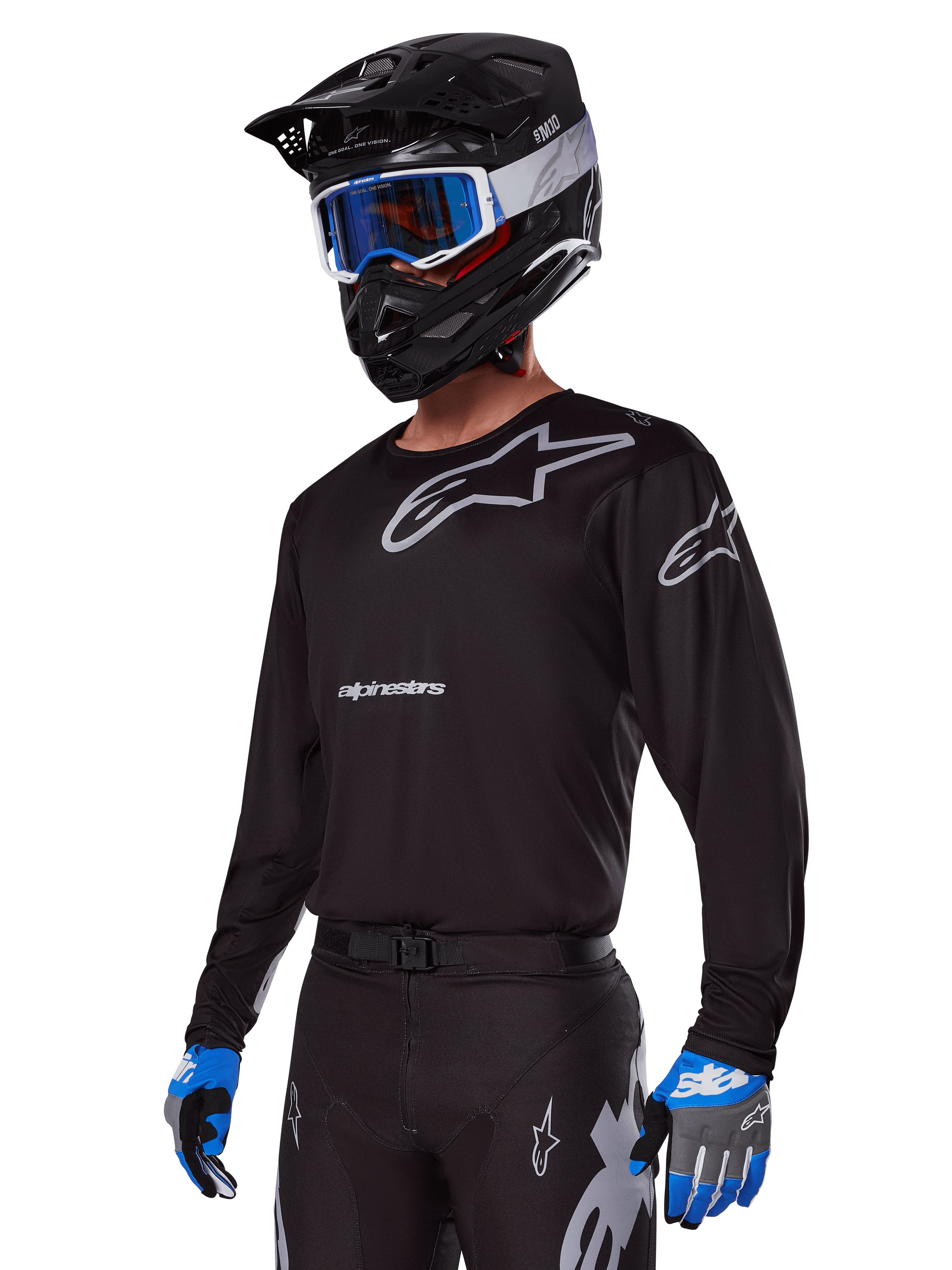 Pilota di motocross con Set Gear Alpinestars Racer Graphite 2025, maglia nera con loghi Alpinestars grigi, pantaloni neri coordinati con dettagli grigi, casco nero con occhiali blu e bianchi, guanti blu e grigi, abbigliamento tecnico per corse fuoristrada