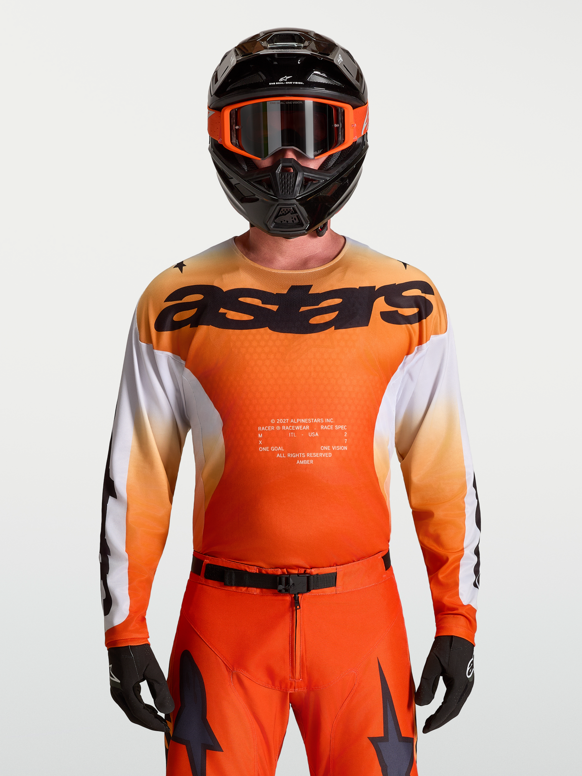 Alpinestars Maglia Racer Amber, maglia da motocross da uomo, arancione e bianca, indossata da un pilota con casco e maschera coordinati, tessuto tecnico traspirante per prestazioni fuoristrada
