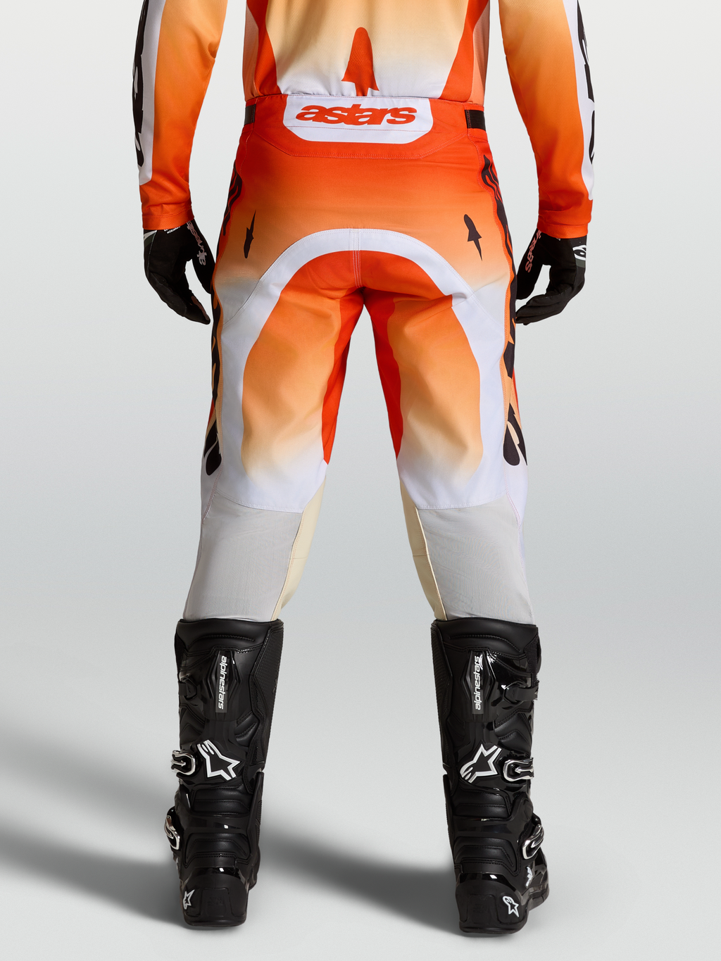 Alpinestars Pantaloni Racer Amber, pantaloni da motocross rossi e bianchi, vista posteriore su modello con stivali neri.