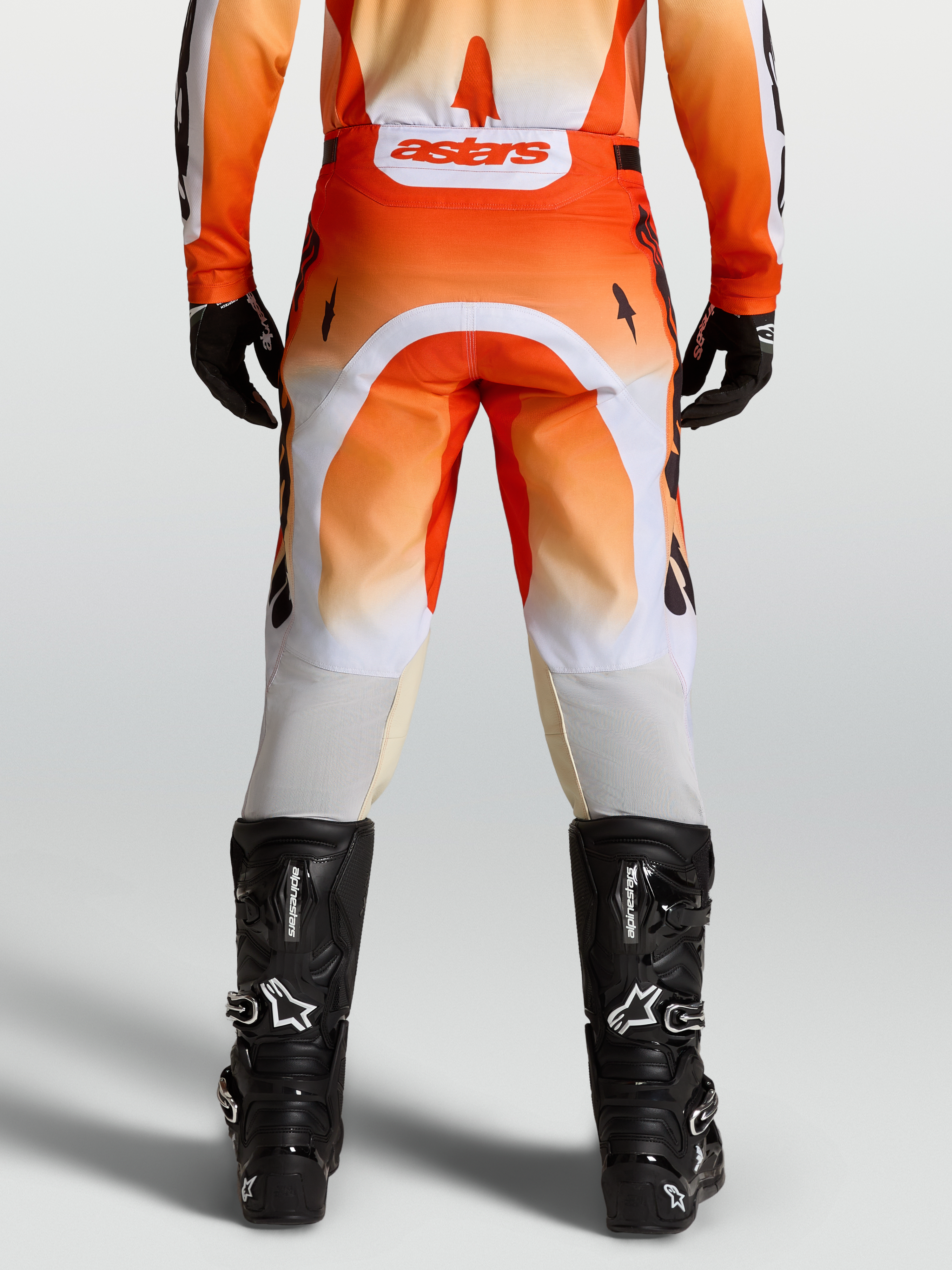 Alpinestars Pantaloni Racer Amber, pantaloni da motocross rossi e bianchi, vista posteriore su modello con stivali neri.
