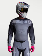 Alpinestars Maglia Racer Amber, maglia da motocross per uomo, grigia e antracite, in poliestere traspirante, indossata con casco e guanti rosa