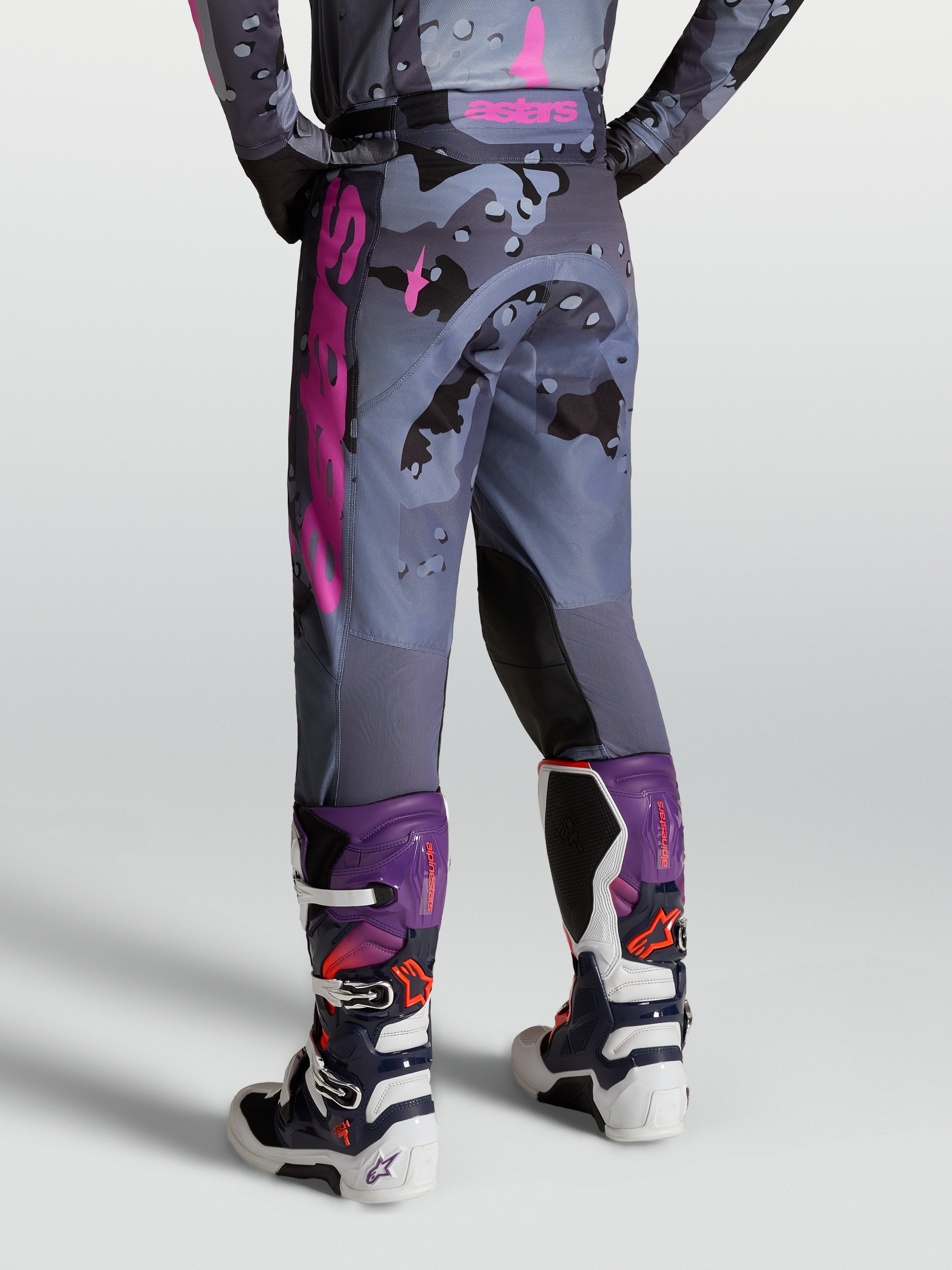 Alpinestars Pantaloni Racer Lone, pantaloni da motocross grigio camo e viola, vista posteriore su modello con stivali Tech 7.