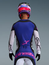 Vista posteriore di un pilota di motocross che indossa la Maglia Techstar Knif 2026 in Nero Grigio Chiaro Viola, caratterizzata da un pannello posteriore viola con logo Alpinestars rosa, maniche grigio chiaro con dettagli neri e traforature tagliate al laser, coordinata con casco rosa e viola e guanti neri.